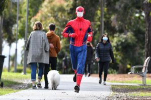 Spiderman jugging in a park wearing face mask